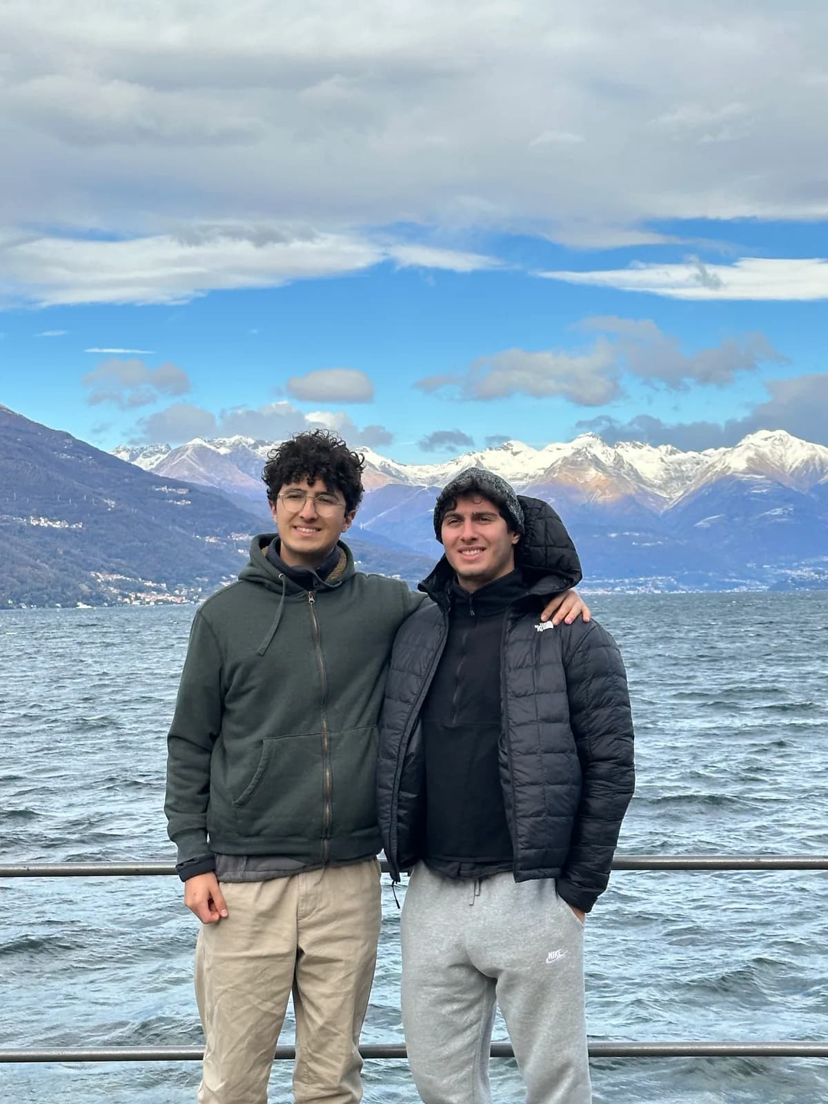 Efe Dincaslan by the water at Lake Como, Italy, with the Alps behind